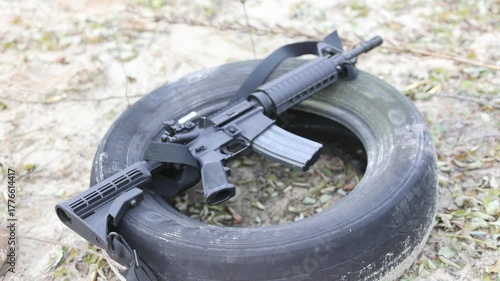 An assault rifle rests on a tire at a training ground. Concept for combat training, security, and modern warfare