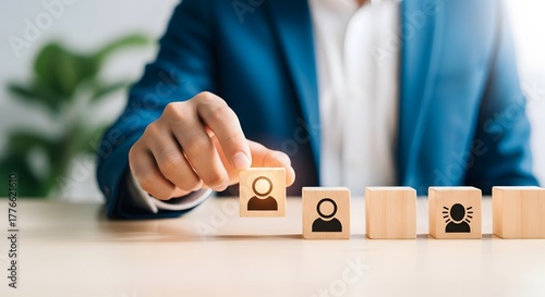 Businessman selecting a person icon from wooden blocks