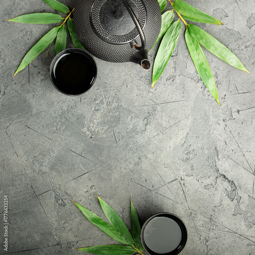 Asian Tea Set with Ginger and Green Leaves on Dark Stone Background