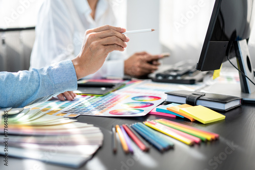 Two creative graphic designer team working on color selection and drawing on graphic tablet, Color swatch samples chart for selection coloring in inspiration to creativity at workplace