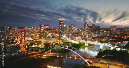 Downtown district of Nashville city in Tennessee, USA at night. Cars drive on Korean Veterans Memorial Bridge over Cumberland river. American travel destination.