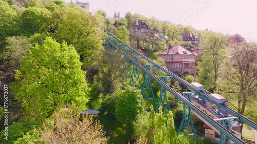 Drohnenflug über die Dresdner Bergbahn Schwebebahn  Bergbahn am Tag. Zwei Bahnen fahren aneinander vorbei, umgeben von viel Grün, Bäumen und einigen Häusern am Hang.