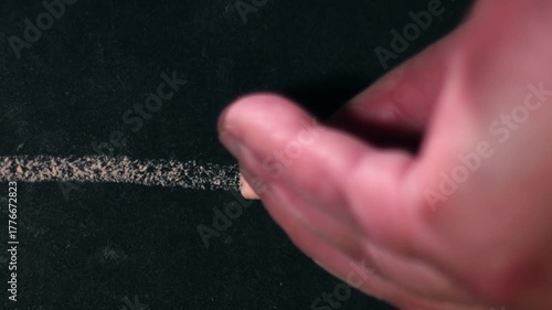 Hand drawing a straight line on chalk black board 