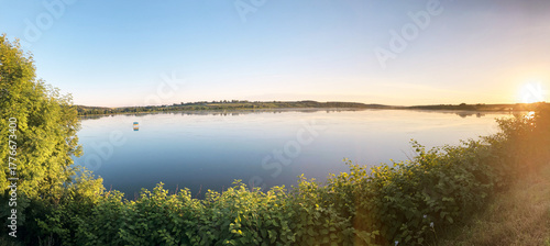 Sunny lake view with light green trees and blue sky. Tranquil landscape perfect for meditation. Breathtaking scenery of rural area Protect the planet Earth. Eco tourism. Travel to remote location
