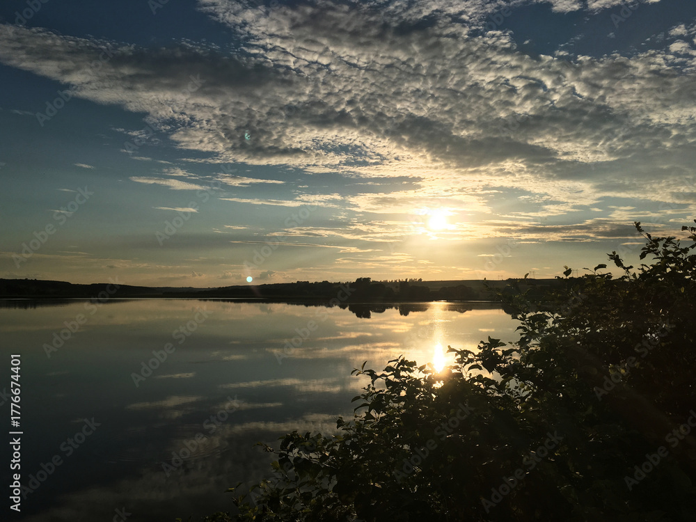 Naklejka premium Beautiful sunset over the lake in the evening. Tranquil scenery in the countryside. Deep meditation in the nature. Magical hour of dim soft light for photography. Panoramic view of the pond.