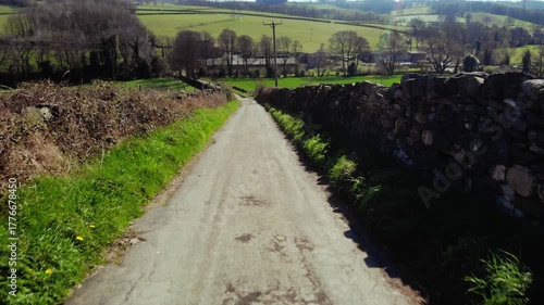 Track road through green fields in British countryside drone aerial 