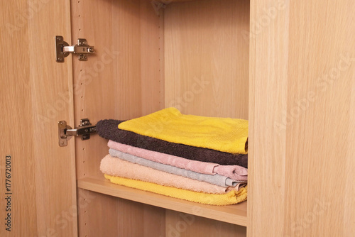 neat stack of folded terry towels rests on a shelf inside a linen closet