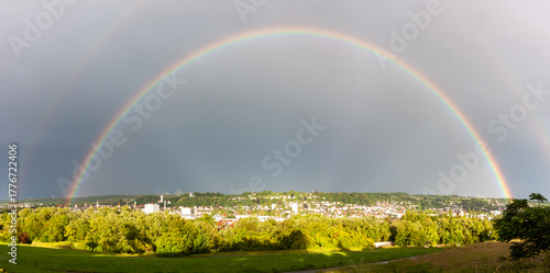 Stunning wide-angle shot of a double rainbow arching over the German city of Ravensburg under a dramatic grey sky