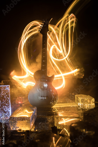 Music Concept: Guitar Miniature on a Dark Background with Vivid Light, Smoke, and Fire Effects. Golden electro guitar under a Dramatic Spotlight.