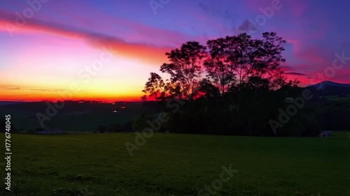 Vibrant sunset paints the sky with hues of purple, pink, and orange over a tranquil landscape.