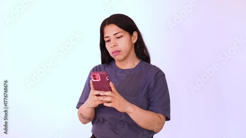 Woman in blue T-shirt isolated on white background looking at her cell phone