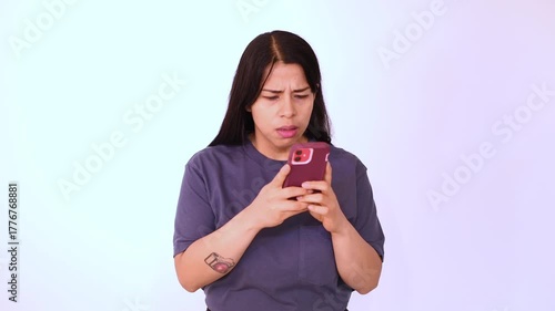 Woman in blue T-shirt isolated on white background looking at her cell phone, consternated