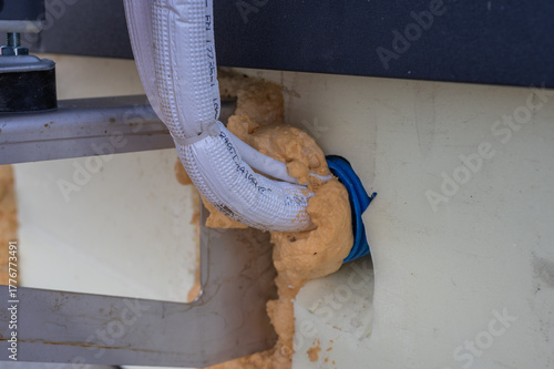 Close-up of insulated air conditioning pipes sealed with polyurethane foam in building wall installation.