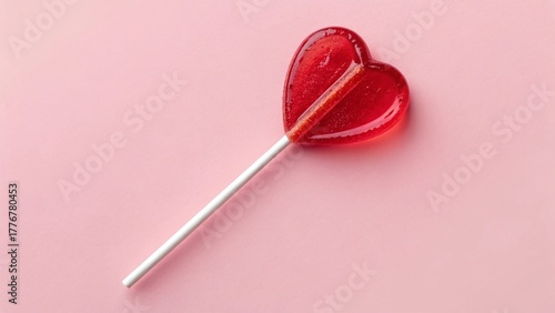 Red heart-shaped lollipop on pink background