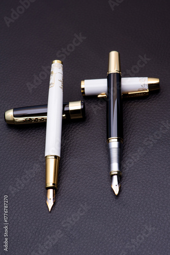 Fountain pens, beautiful details of fountain pens positioned on a black surface, low key photo, selective focus.