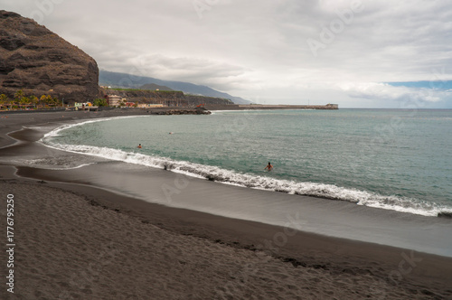 Langgezogener halbrunder Strand mit dunklem Lavasand