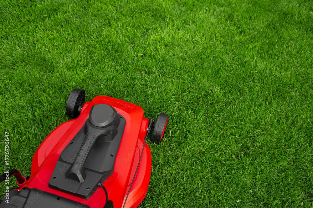 Fototapeta premium Red and black lawn mower on the lawn.