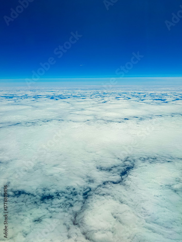 Vast expanse of fluffy clouds under a clear blue sky at high altitude during midday flight