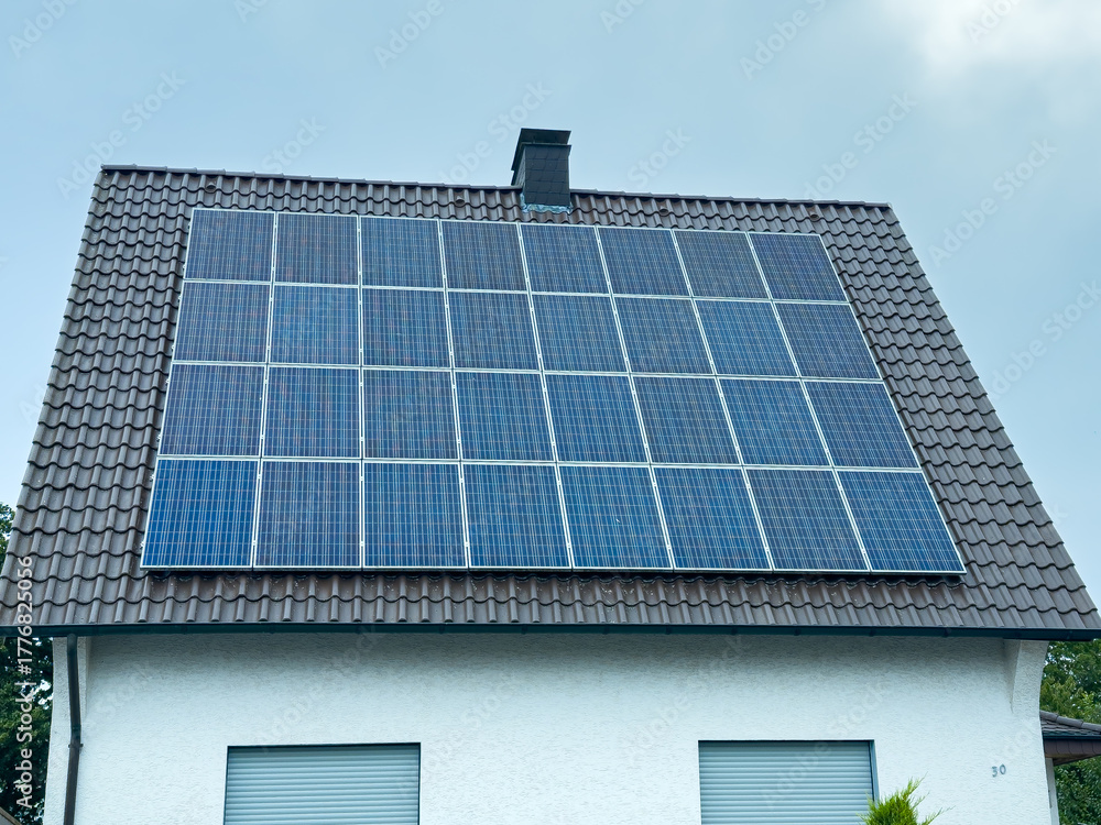 Fototapeta premium Innovative solar panels harnessing renewable energy on a suburban house roof in bright daylight