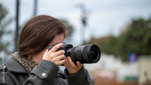 Young Woman Capturing Moments With a Camera During an Outdoor Event on a Cloudy Day
