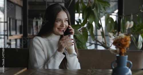 Woman talking by mobile phone in a cafe drinking latte