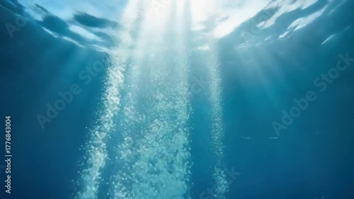 A mesmerizing view capturing the dance of light and bubbles rising in the depths of ocean. The ethereal glow and the vibrant blue evoke a sense of tranquility and exploration.