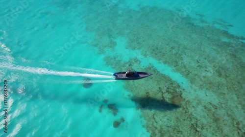 A sleek speedboat glides effortlessly across the vibrant turquoise waters, leaving a trail of white in its wake, embodying the essence of speed and nautical prowess.