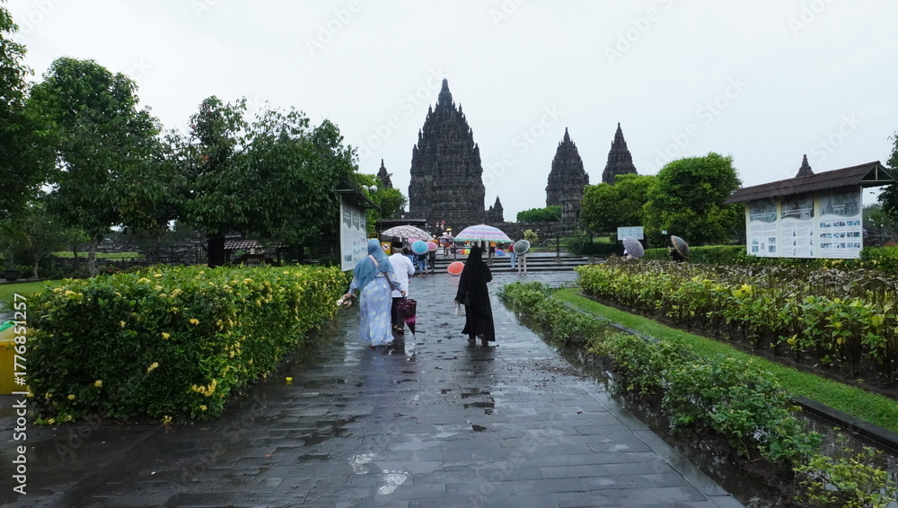 Obraz premium Visitors Walking Toward Ancient Temple on Rainy Day