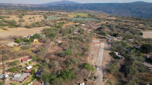 Forward aerial shot flying above El Chilar and heading toward crop fields in a dry rural setting