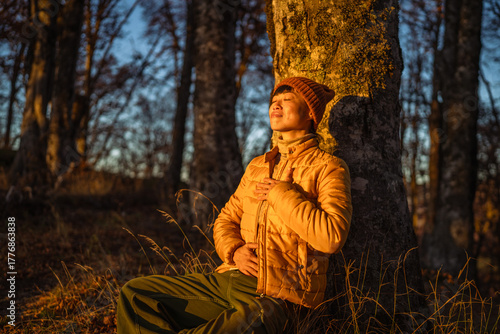 Person meditating in forest at golden hour