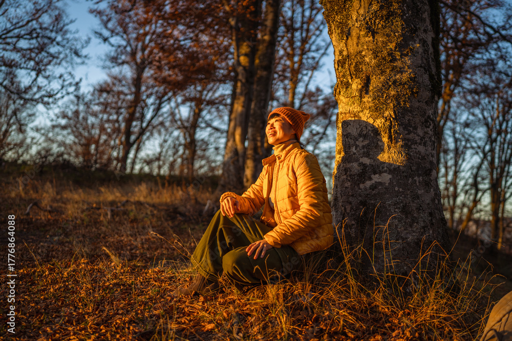 Fototapeta premium Woman smiling relaxing a golden hour forest