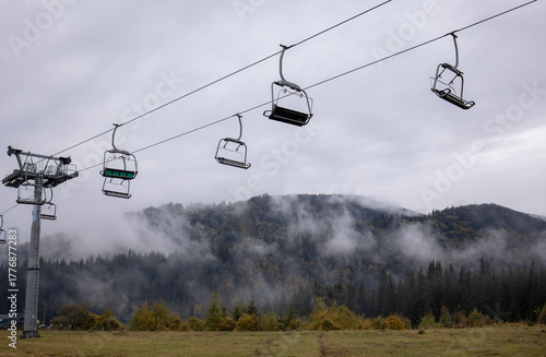 Ski lift without people on the background of mountains, clouds and fog