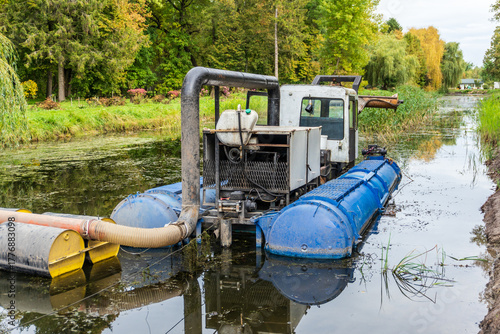 Obraz na płótnie Machine clears waterway of algae and debris in a tranquil rural setting