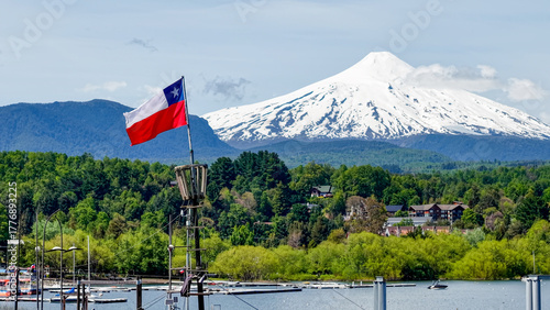Close-up of the Chilean flag waving in the port of the city of Pucón, with the imposing Villarrica volcano in the background.