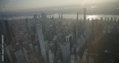 Light beams from sunrise shining on beautiful Manhattan skyscrapers - helicopter shot 