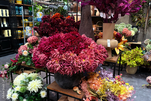 Bild auf Leinwand Bold red and pink faux chrysanthemums arranged in textured floral displays for indoor retail styling