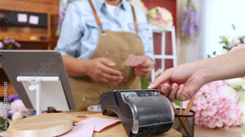 Senior woman, florist shop, small business owner accepts contactless payment by credit card, showing technology confidence in cashless generation, digital banking for aging entrepreneur, mobile POS