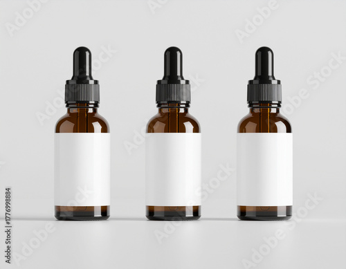 Three small amber glass dropper bottles with blank white labels and black caps, aligned against a plain background. Ideal packaging template for essential oils or serums.