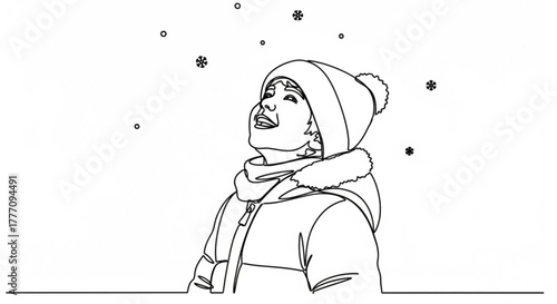 Young child smiling and looking up at falling snowflakes in winter  