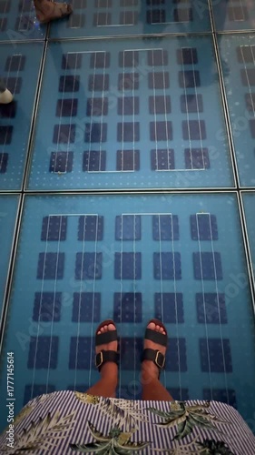 personal perspective, woman standing on solar panel glass floor with lights and people walking around in Zadar, Croatia