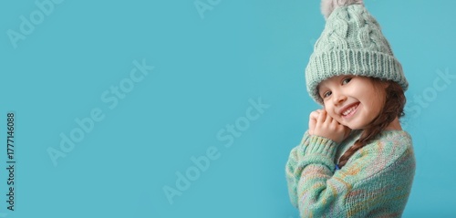 Smiling little girl in winter clothes on blue background with space for text