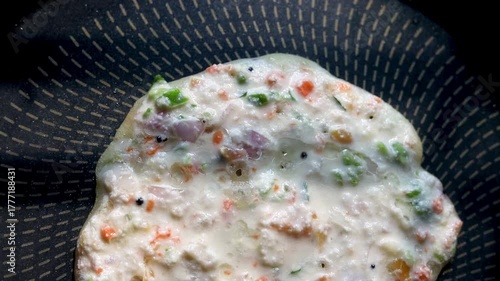 Indian chilla or uttapam prepared on black pan in kitchen with sunlight