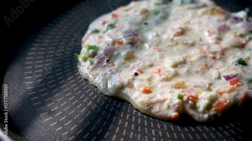 Indian chilla or uttapam prepared on black pan in kitchen with sunlight