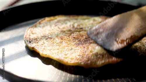 Indian chilla or uttapam prepared on black pan in kitchen with sunlight