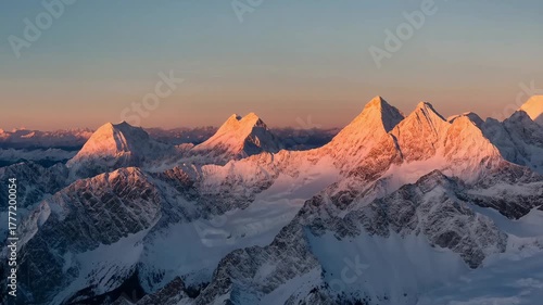 Snow-capped mountains illuminated by sunset during twilight sky  