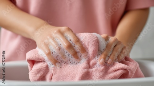 Close Up of Hands Washing a Pink Shirt in Soapy Water, Capturing the Routine of Cleaning Clothes with Care and Attention to Detail