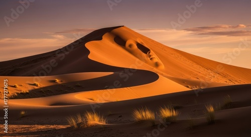 Fototapeta Naklejka Na Ścianę i Meble -  A majestic sand dune in the Sahara Desert at sunset, with a serene sky and golden sand.