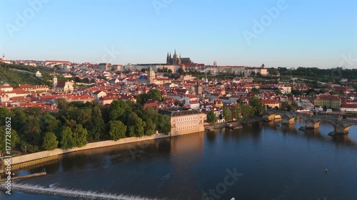 Aerial drone footage beautifully showcases the enchanting city of Prague, highlighting the historic Karlov Bridge and the serene Vltava River flowing through the picturesque landscape. Czech Republic