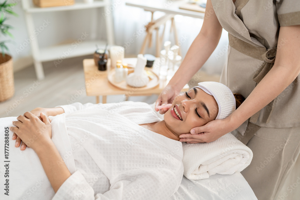 Obraz premium Beautiful woman getting facial massage with gua sha at beauty spa.