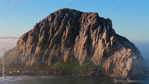 Scenic view of Morro Rock at Morro Bay California surrounded by gentle Pacific Ocean waves under clear blue sky capturing natural beauty, coastal landscape and famous California landmark